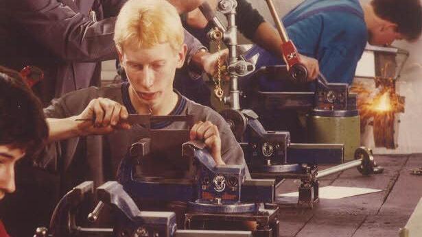 Der ehemalige Ausbildungsmeister Horst Biemann (Mitte links) 1990 bei der Arbeit in der Lehrwerkstatt. Die Lehrlinge feilen, messen, schleifen und löten unter seiner Anleitung.  Foto: Maschinenfabrik Fischer