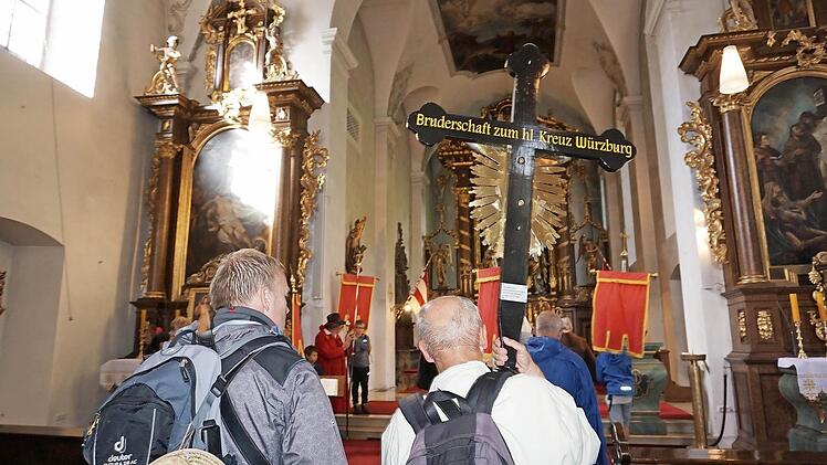 Das Kreuz mit der Aufschrift "Bruderschaft zum Heiligen Kreuz Würzburg" wird in die Klosterkirche am Kreuzberg getragen. Foto: Eckert