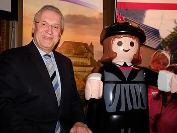 Bayerns Innenminister Joachim Herrmann (CSU) posiert mit einem Playmobil-Luther vor einem Foto der Veste Coburg. Foto: Nikolas Pelke