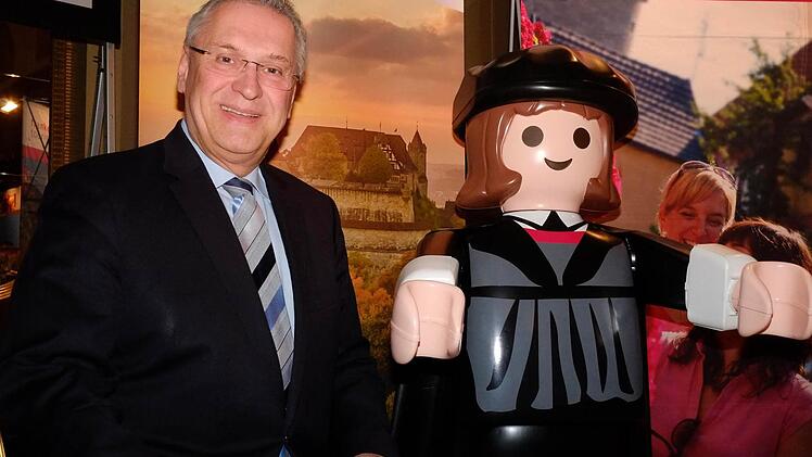 Bayerns Innenminister Joachim Herrmann (CSU) posiert mit einem Playmobil-Luther vor einem Foto der Veste Coburg. Foto: Nikolas Pelke