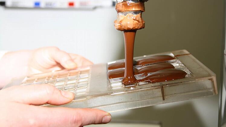 In einem dicken Strom fließt die flüssige Schokolade in die Formen.