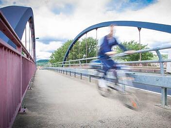 Sommerzeit ist Radlzeit: Ein Mann überquert die Mainbrücke von Zeil in Richtung Sand. Seine Kleidung hat er wohl zufällig auf die Brückenfarbe abgestimmt. Foto: Hendrik Steffens
