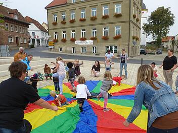 Die Kinder spannen am Marktplatz ein großes Schwungtuch. Foto: Kita
