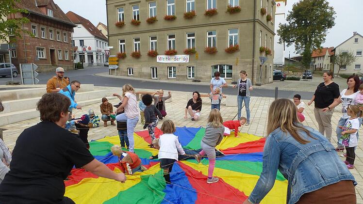 Die Kinder spannen am Marktplatz ein großes Schwungtuch. Foto: Kita