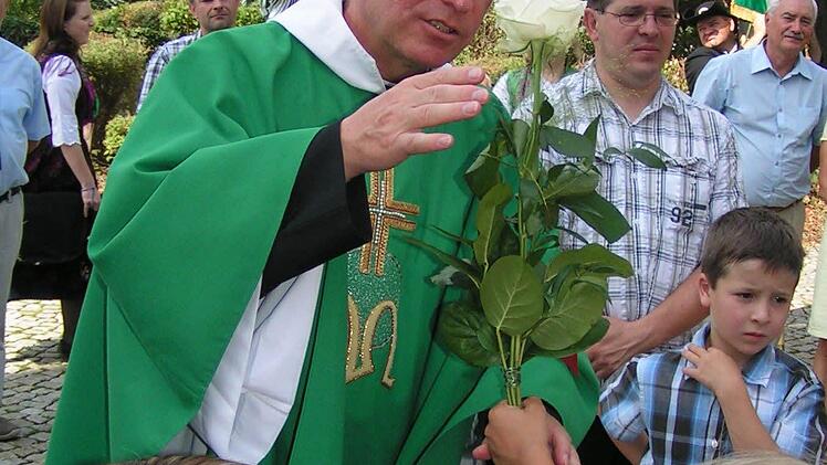 Pfarrer Gerhard Möckel bekommt Rosen überreicht von den Kiga-Kindern. Foto: Heidi Amon