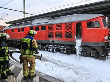 Feuerwehrleute löschen am Bahnhof Erlangen mit Schaum eine Diesellok eines Güterzuges, die Feuer gefangen hatte. Foto: News5/Merzbach
