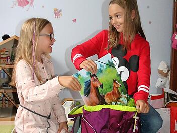 Gut, eine ältere Schwester zu haben: Die neunjährige Lena (rechts) hilft ihrer sechsjährigen Schwester Viktoria nicht nur beim Packen der Büchertasche, sondern gibt auch Tipps zum Schul-Alltag. Foto: Ralf Ruppert