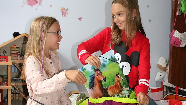 Gut, eine ältere Schwester zu haben: Die neunjährige Lena (rechts) hilft ihrer sechsjährigen Schwester Viktoria nicht nur beim Packen der Büchertasche, sondern gibt auch Tipps zum Schul-Alltag. Foto: Ralf Ruppert