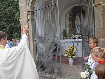 Pfarrer Matthias Steffel weiht die Lourdes-Madonna in der Mariengrotte neben der Kreuzbergkirche ein. Foto: Mathias Erlwein