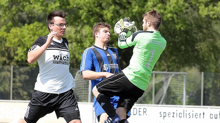 Kreisklasse 3: Burghaslachs Keeper Daniel Hausmann (rechts) klärt vor dem Pettstadter Michael Baldauf (Mitte). Verteidiger Ulrich Rost wäre wohl zu spät gekommen. Fotos: Sportpress