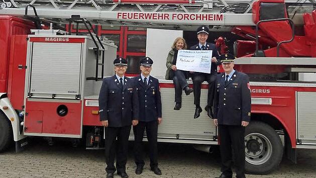 Hoch auf dem roten Wagen: Feuerwehrvereinsvorsitzender Josua Flierl und Heilp&auml;dagogin Anna Stein mit dem Spendenscheck.  Foto: Franka Struve