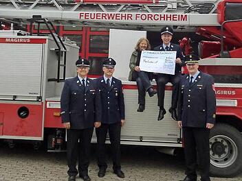 Hoch auf dem roten Wagen: Feuerwehrvereinsvorsitzender Josua Flierl und Heilpädagogin Anna Stein mit dem Spendenscheck.  Foto: Franka Struve
