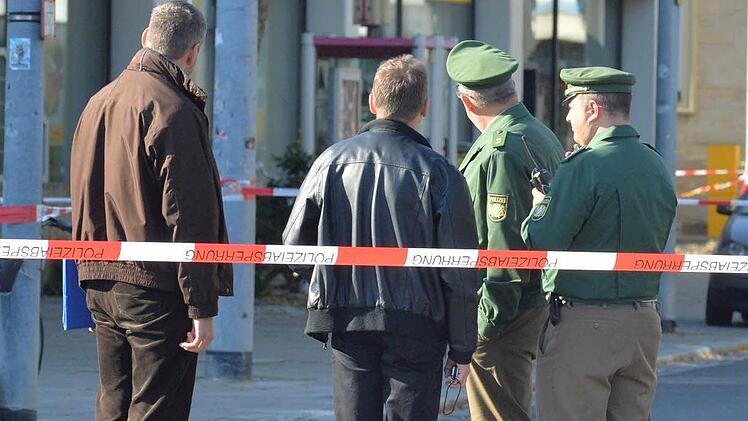 Die Polizisten blicken auf die beiden Telefonzellen im Hintergrund. In der rechten befand sich die Tasche mit der Bombendrohung. Foto: Ronald Rinklef