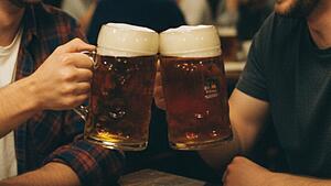 Zwei Kumpels um die 30 stoßen mit 0,5-Liter Krügen voller Bockbier an.
