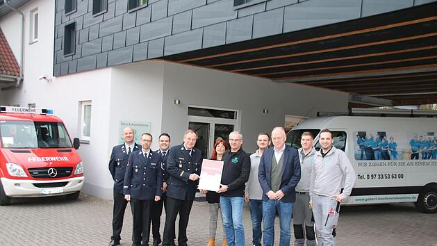 Kreisbrandrat Benno Metz &uuml;bergibt im Beisein der Feuerwehrf&uuml;hrung und der Mitarbeiter die Urkunde an Udo Gebert.  Foto: Thomas Malz
