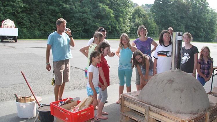 Gespannt schauen die Kinder der Juniorakademie und Oliver Leimenstoll, ob der Lehmofen die Hitze aushält.