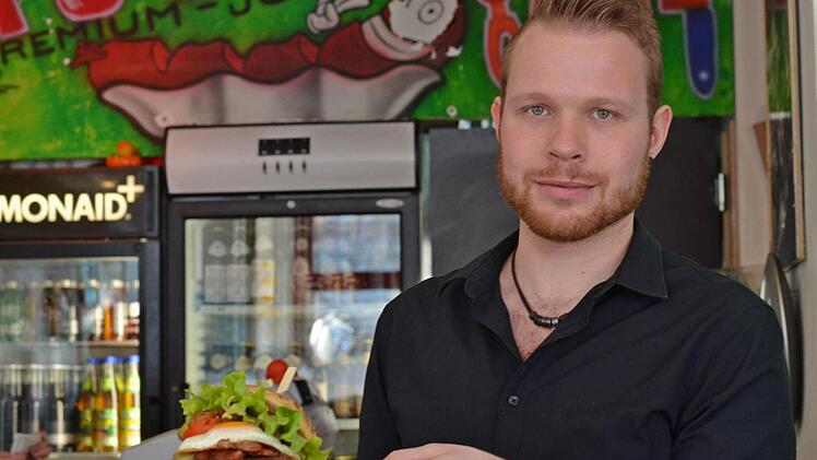 Teammitglied Manuel vom Nürnberger Burger-Laden "Auguste" serviert einen Burger für Feinschmecker. Foto: Pelke