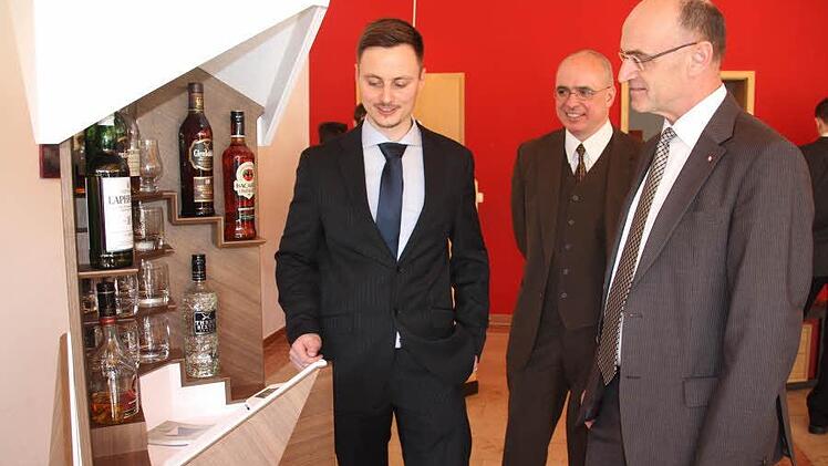 Angetan von der "Hub-Bar" des 24-jährigen Schreinermeisters Tobias Weck (links), die mittels einer App geöffnet wird, war Landrat Wilhelm Schneider (rechts), auch wenn ihm vom Konstrukteur daraus kein "Drink" angeboten wurde. Schulleiter Dr. Oliver Dünisch (Mitte) blickt ebenfalls wohlwollend auf das Meisterstück. Foto: Helmut Will
