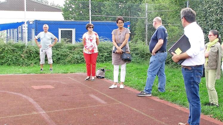 Die Ausschussmitglieder sind auf dem s&uuml;dlichen Teil des Hartplatzes, wo zur Kindergarten-Erweiterung Module aufgestellt werden k&ouml;nnten.