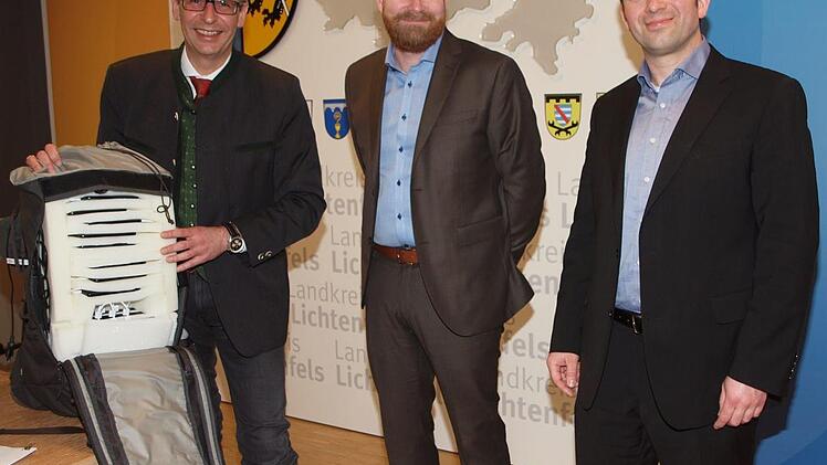 Landrat Christian Meißner, Mats Nordström, Chef der schwedischen Firma IQMTEL und Björn Meschenmoser (von links), der Geschäftsstellenleiter der Firma für Deutschland, präsentieren den mit neun speziellen Smartphones bestückten Rucksack, der zur Bestimmung der Qualität des Mobilfunknetzes auf Wanderwegen zum Einsatz kommt.  Foto: Alfred Thieret