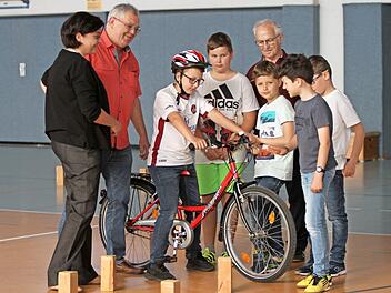 Rektorin Jutta Aumüller mit den MSC-Mitgliedern Jürgen Kolbert und Erich Klarmann (von links) und den Schülern an einem Fahrrad, an dem sie gerade die Ausstattung für die Verkehrssicherheit überprüfen, die ebenfalls zum Wettbewerb gehören. Foto: Günther Geiling