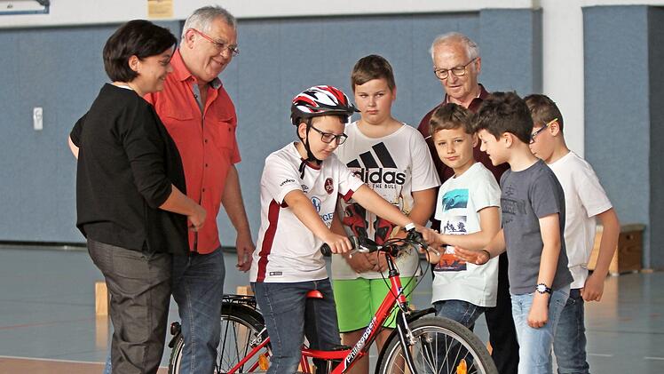 Rektorin Jutta Aumüller mit den MSC-Mitgliedern Jürgen Kolbert und Erich Klarmann (von links) und den Schülern an einem Fahrrad, an dem sie gerade die Ausstattung für die Verkehrssicherheit überprüfen, die ebenfalls zum Wettbewerb gehören. Foto: Günther Geiling