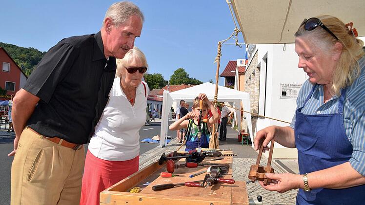 Annemarie Leuschner hatte diesmal allerhand Werkzeuge aus Schreiner- und Tischlerwerkstätten zusammengetragen. Hier zeigt sie Marlis und Roland Jäger aus Waldfenster ihr ältestes Stück - ein Stellmaß aus dem 17. Jahrhundert. Währenddessen probiert der achtjährige Jonas im Hintergrund den Handbohrer aus.