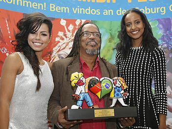 Fernanda Brand&atilde;o (links) und Sara Nuru (rechts) mit einem Musiker der brasilianischen Gruppe "Olodum", der den F&ouml;rderpreis Humano in den H&auml;nden h&auml;lt. Foto: Matthias Hoch