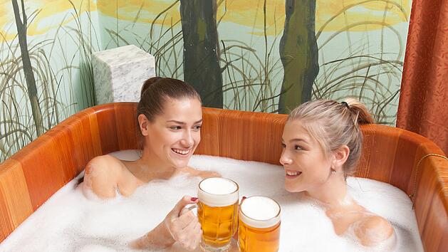 Beautiful girl enjoying a beer bath. Young women relaxing in the beer spa. Bathing in beer. (color toned image). Beautiful women in a beer spa.