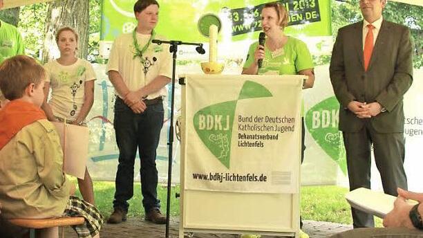 Jutta Laube holt den hereingeschlichenen Landrat Christian Meißner nach vorne und motiviert die Aktionsteilnehmer für das kommende Wochenende. Diese warten währenddessen gespannt auf die Enthüllung der von ihnen zu bewältigenden Aufgaben. Foto: Manuel Stark