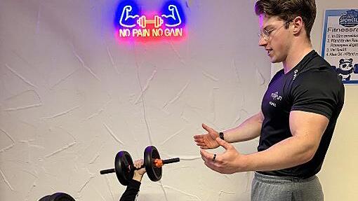 Fitnesstrainer Moritz vom Kulmbacher Fitnessstudio Fit &rsquo;n Fun leitet einen Probanden fachkundig an.