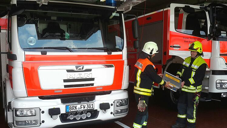 Der große Einsatzwagen der Bad Brückenauer Floriansjünger mit der Drehleiter  (links im Bild) fährt prophylaktisch immer mit, wenn die Feuerwehr zu einer Türöffnung angefordert wird. Und natürlich darf der Behälter mit dem Spezialwerkzeug nicht fehlen, den Gerätewart Sven Gerhard gerade an Kommandant Michael Krug (rechts) übergibt. Foto: Rolf Pralle