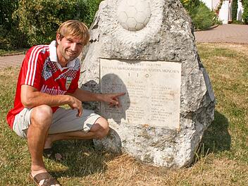 Roland Steins Name ist auf dem 1:0-Gedenkstein vor dem Sportheim in Vestenbergsgreuth verewigt. Fürs Foto hat er noch einmal sein altes Trikot übergestreift. Foto: Archiv