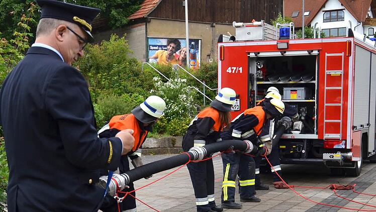 In Sekundenschnelle: Kreisbrandinspektor Ronald Geis stoppt mit einer Uhr, ob die Saugleitung in der vorgegebenen Zeit gekuppelt und mit dem Fahrzeug verbunden wird. Die Feuerwehrler schlagen sich gut. Foto: Kathrin Kupka-Hahn