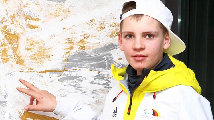 Maxi Jäger in der Montur der deutschen Paralympicmannschaft vor einem seiner Gemälde