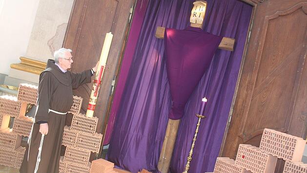 Pater Heribert neben dem heiligen Grab, das in den Kartagen verhüllt ist. Die Backsteine gehören zur "Klagemauer", die vor Ostern am heiligen Grab aufgebaut ist. Foto: Matthias Einwag