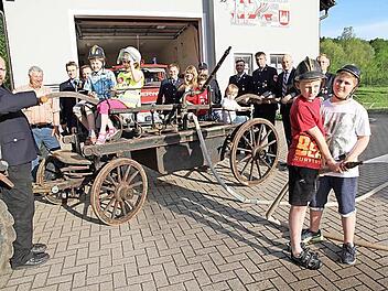 Mitglieder der Wehr, der Feuerwehrnachwuchs und der Schirmherr der Feierlichkeiten, Bürgermeister Claus Schwarzmann, präsentieren die alte Handspritzpumpe.  Foto: Mathias Erlwein