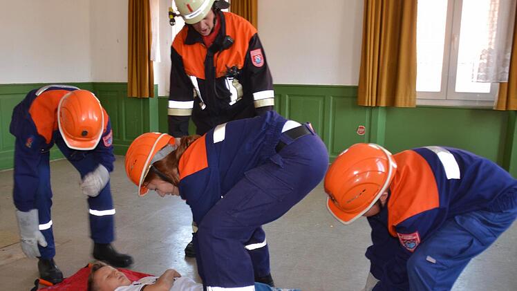 Wohnhausbrand in Waldfenster: Der Stralsbacher Feuerwehrnachwuchs rettet einen Bewusstlosen, dargestellt von Rico Seller. Im Hintergrund ist der Waldfensterer Kommandant zu sehen, der Tipps gibt, wie die Jugendlichen das am besten bewerkstelligen.Foto: Kathrin Kupka-Hahn