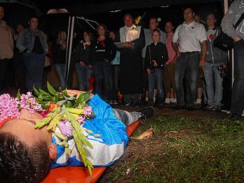 Bastian Reichelsdorfer liegt auf der Bierbank, Blumen auf dem Bauch. "Pfarrer Kreuzer" leitet den Trauerzug. Fotos: Andreas Brandl