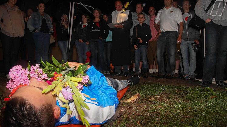 Bastian Reichelsdorfer liegt auf der Bierbank, Blumen auf dem Bauch. "Pfarrer Kreuzer" leitet den Trauerzug. Fotos: Andreas Brandl