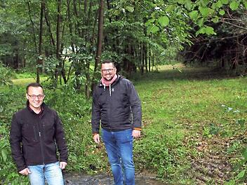 Jan Strobel und Jochen Bergmann zeigen den kleinen Bachlauf, an dem sie sich einen Wasserspielplatz vorstellen könnten. Der Weihersbach liegt nur wenige Meter neben dem Parkplatz unterhalb der Schule - unweit des Baugebietes "Am Wald". Foto: Sonny Adam