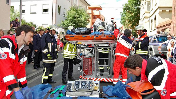 Während Notarzt Ralph Brath den Verletzten bei der Rettungsübung noch an der Feuerwehr-Drehleiter versorgt (hinten), bereiten BRK-Sanitäter (vorn) das Umbetten vor.