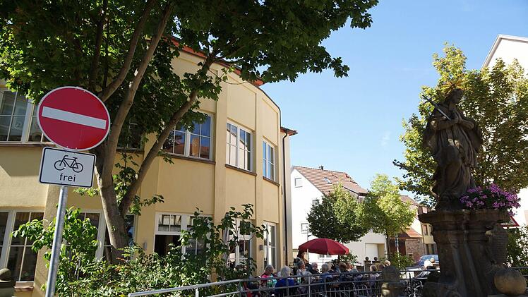 Bewohner des Bürgerspitals im Schatten von Bäumen und der Heiligenfigur. Foto: Arkadius Guzy