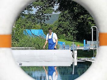Bernd Illig entfernt am Mittwoch die Temperatur-Isoliermatten vom Schwimmerbecken. Sie sollen das Auskühlen verhindern. Fotos: Thomas Heuchling