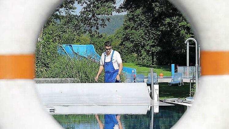 Bernd Illig entfernt am Mittwoch die Temperatur-Isoliermatten vom Schwimmerbecken. Sie sollen das Auskühlen verhindern. Fotos: Thomas Heuchling