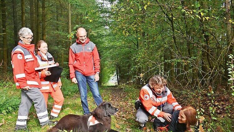Die gefundene Person musste der Hund anzeigen und bei ihr bleiben, so wie hier der sechsjährige Aron, ein Hovawart, bis sein Frauchen, Brigitte Lutz von der Hundestaffel Hassfurt, vor Ort war und erste Hilfe leisten konnte. BRK Kreisgeschäftsführer Hubert Kießner ließ sich von der Begleit-Prüferin Michaela Hanika und Prüferin Maria Hoffmann die Situation erläutern.  Foto: Hanns Friedrich