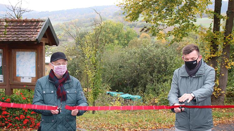 Stellvertretender Landra Gotthard Schlereth  (links) und Hammelburgs Bürgermeister Armin Warmuth gaben den neuen Wanderweg "Kalk und KulTOUR - Erleben in der Natur"  in Obereschenbach offiziell frei, indem sie ein rotes Band durchschnitten. Foto: Hilmar Ruppert