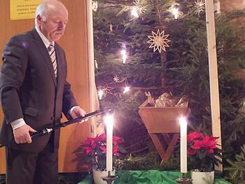Mesner Georg Wluka zündet die Kerzen neben der Figur des Christkindes an. Foto: Manfred Welker
