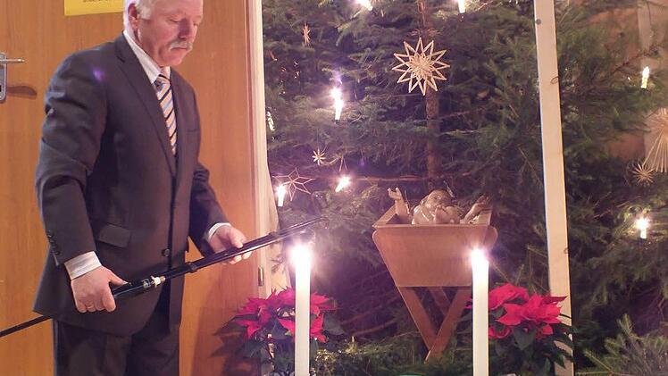 Mesner Georg Wluka zündet die Kerzen neben der Figur des Christkindes an. Foto: Manfred Welker