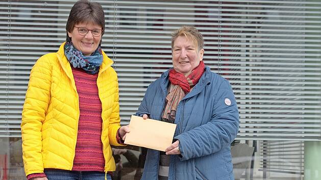 Uschi Schmidt übergibt Elfriede Höhn den Umschlag mit den Spendengeldern.